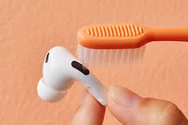 Gently brushing earbud speaker mesh to remove earwax