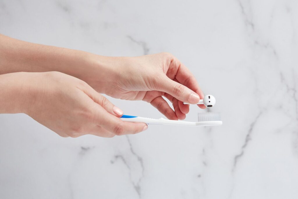 Gently brushing earbud speaker mesh to remove earwax