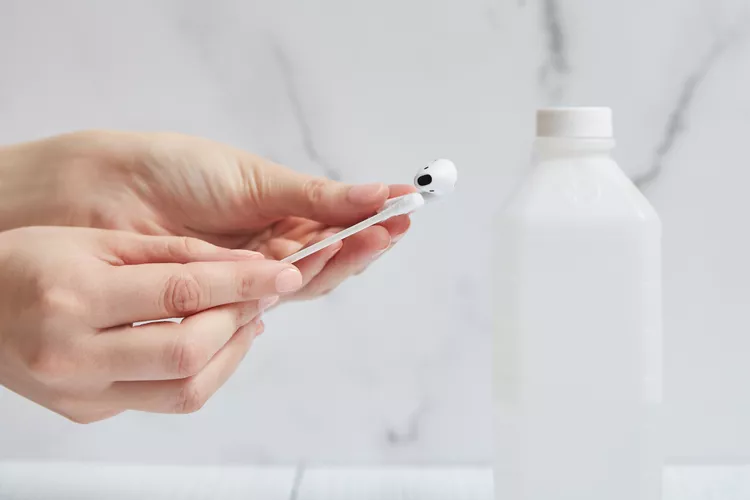 Using cotton swab with isopropyl alcohol to clean earbuds